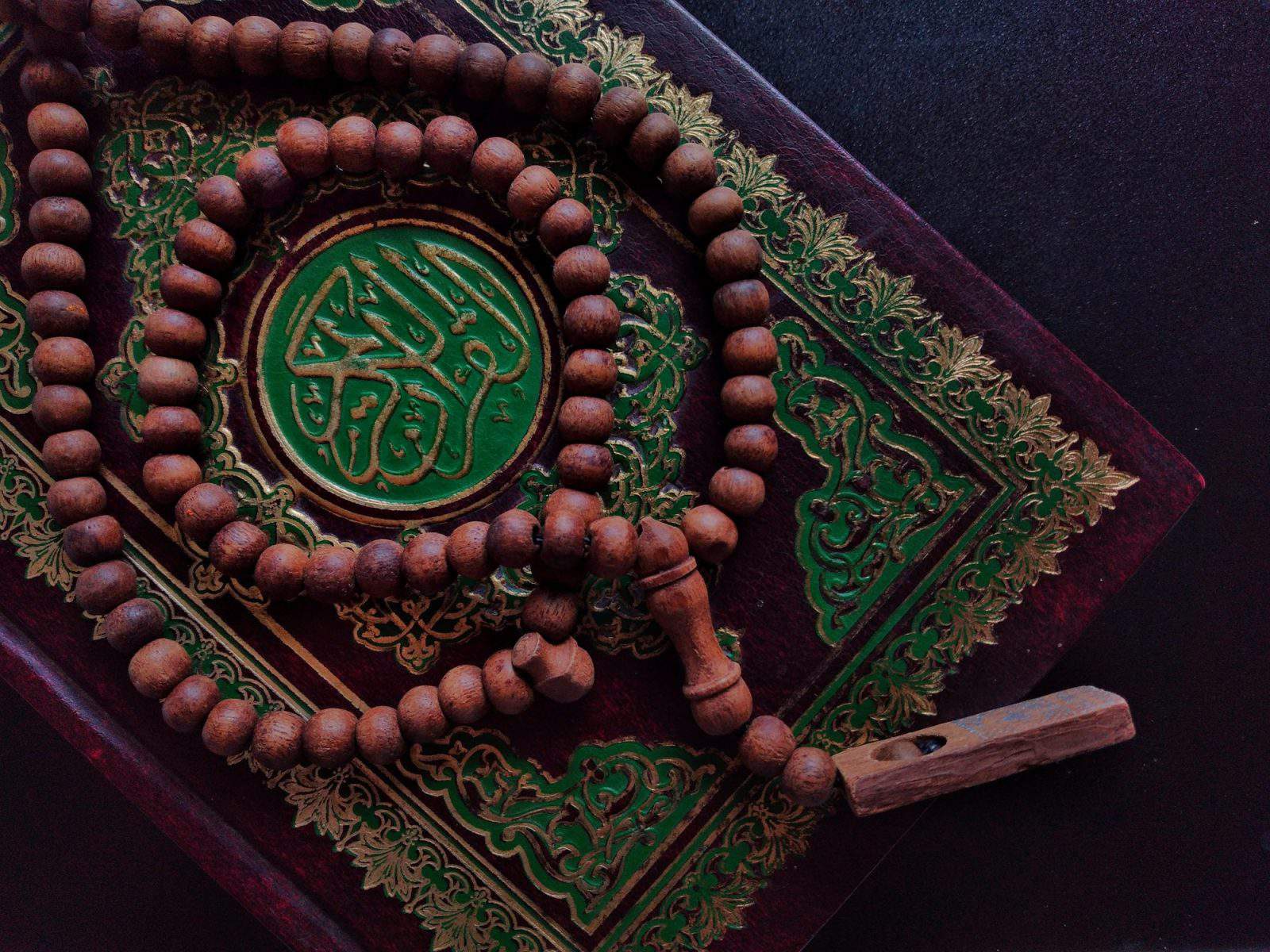 Holy Quran written arabic calligraphy meaning of Al Quran and Rosary beads