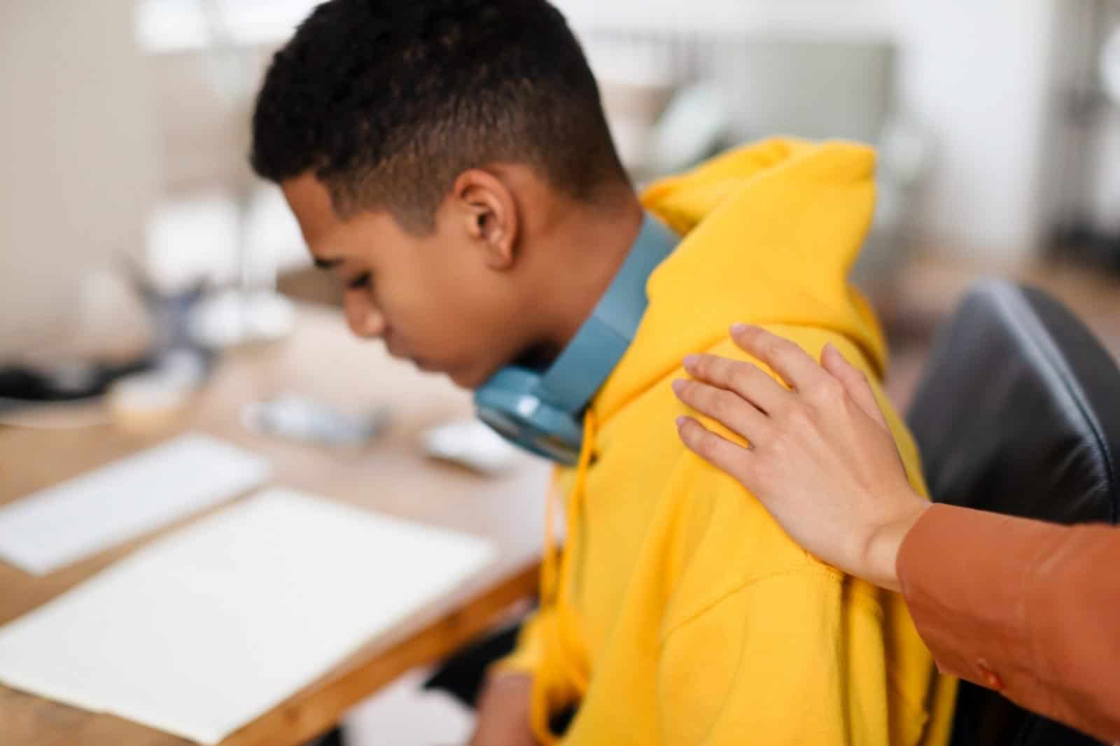 Young person receiving comforting hand on shoulder